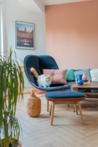 Salon lumineux et coloré avec fauteuil bleu confortable et éléments décoratifs ludiques, créant une ambiance accueillante et chaleureuse