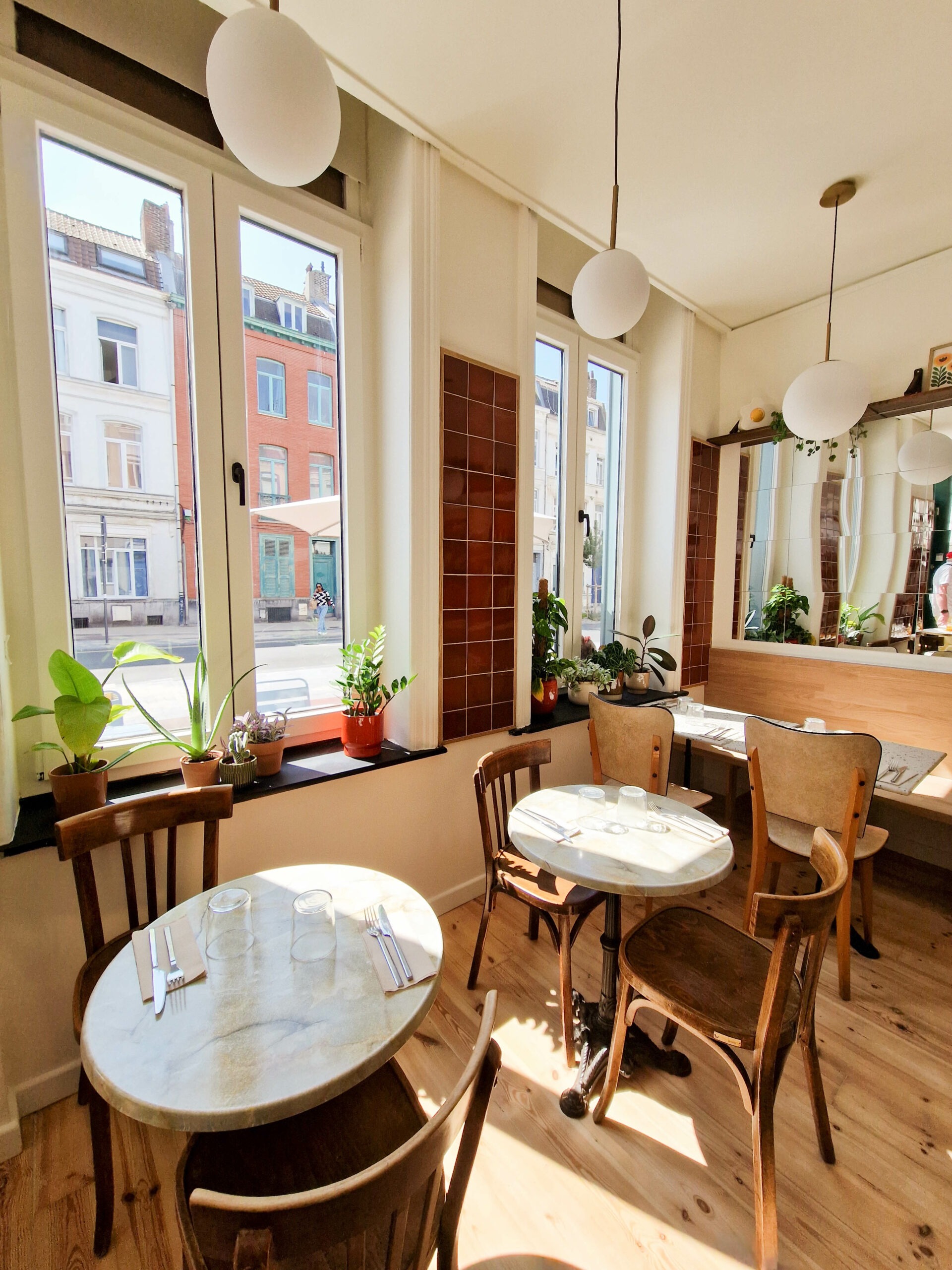 Aménagement du restaurant Pickles à Lille avec tables près des fenêtres, lumière naturelle et ambiance chaleureuse