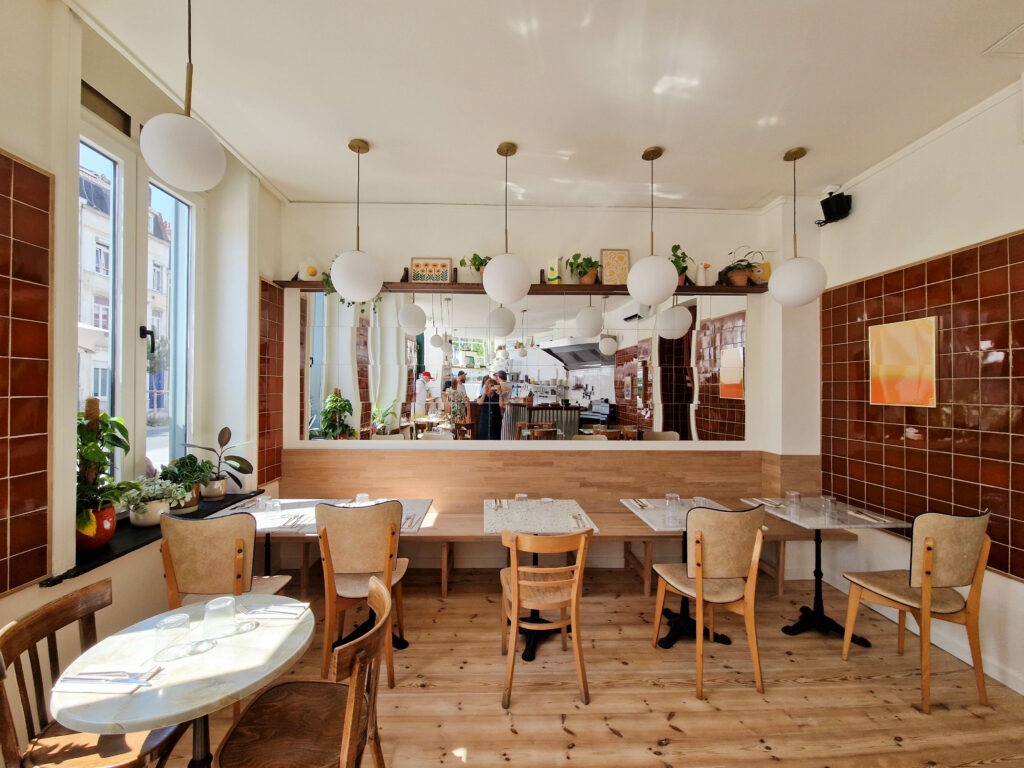 Aménagement intérieur du restaurant Pickles à Lille avec salle lumineuse, matériaux bois et vue sur la cuisine