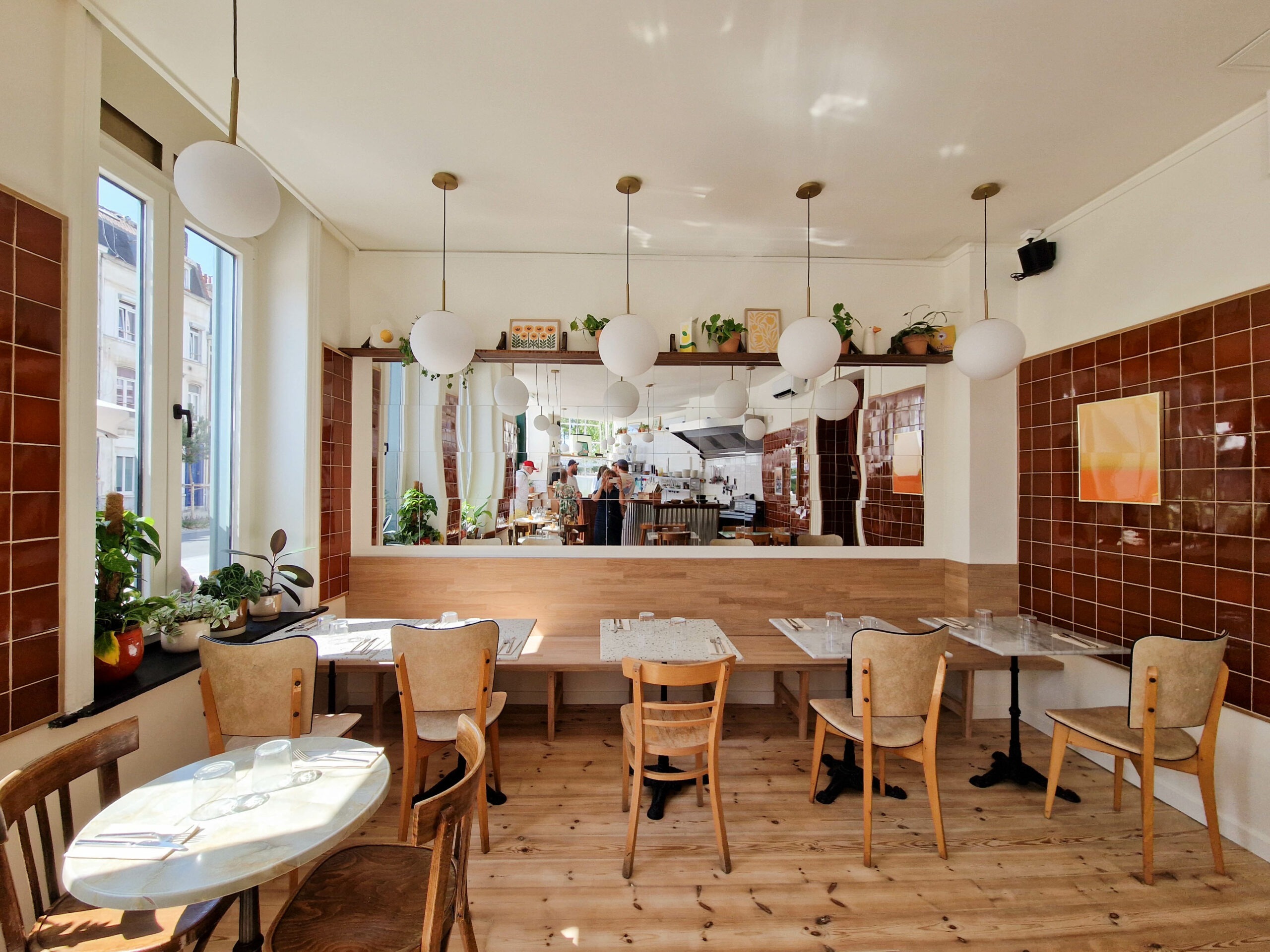 Aménagement intérieur du restaurant Pickles à Lille avec salle lumineuse, matériaux bois et vue sur la cuisine